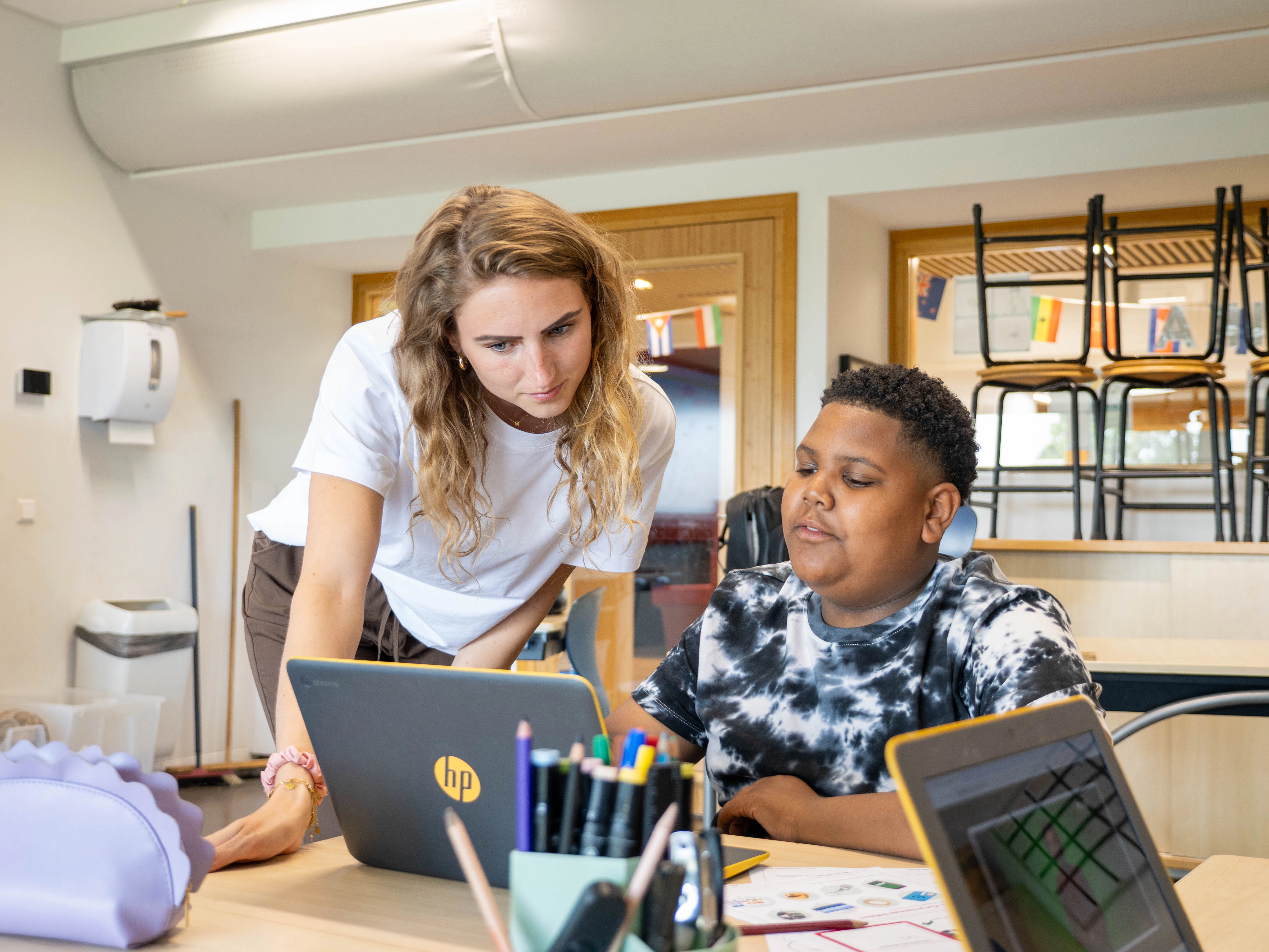 Leerling krijgt uitleg van de juf bij een lesmodule op de laptop.